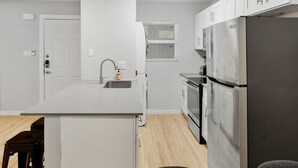 A modern kitchen with white cabinetry, a stainless steel refrigerator, a built-in oven, and a sink. - Stylish 2BR Near UT Hyde Park Evonify (Austin)