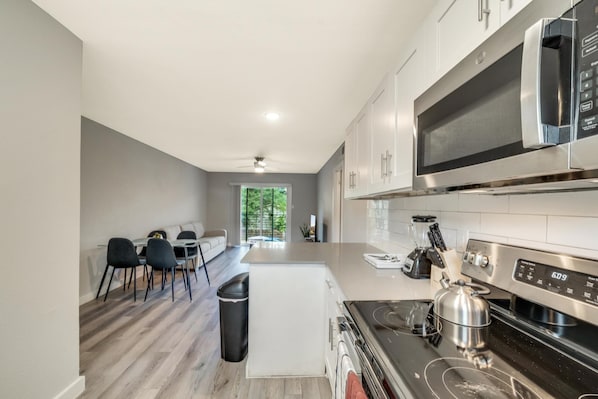 Enjoy meals in this kitchen with a sleek microwave and oven, a dining area, and a view of the surrounding greenery.