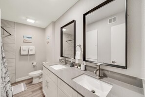 Une salle de bain moderne avec deux lavabos, des toilettes et une douche.