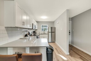 Une cuisine moderne avec des armoires blanches, des appareils en acier inoxydable et un îlot central.