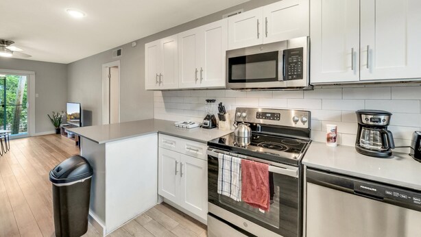 A modern kitchen with white cabinets, stainless steel appliances, and a large window. - Modern 2BR Near UT Hyde Park Evonify (Austin)