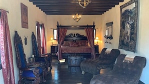 Une chambre à coucher avec un lit à baldaquin, un lustre et un grand tableau accroché au mur.