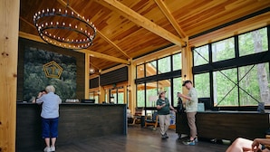 A spacious lobby with a wooden ceiling, large windows, and a reception desk. - Terramor Outdoor Resort (Bar Harbor)
