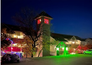 Una zona residencial con casas, una estructura pequeña parecida a una torre y un cartel iluminado en verde.