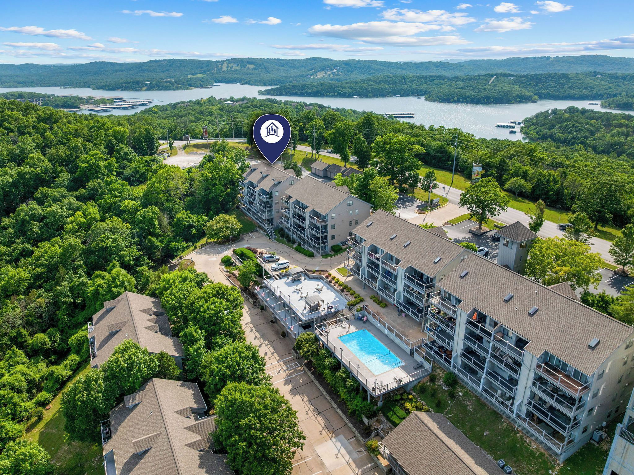 Un hôtel à plusieurs étages doté d’une piscine, entouré d’une végétation luxuriante et offrant une vue sur un lac.