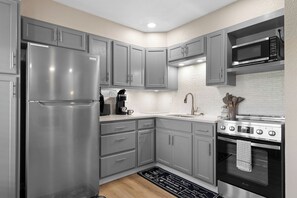 Una cocina moderna con armarios grises, electrodomésticos de acero inoxidable, un microondas integrado y una estufa a gas.