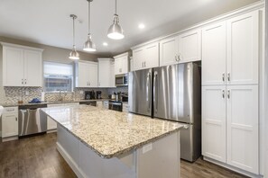 A modern kitchen with white cabinets, stainless steel appliances, granite countertops, and pendant lighting. - Top Lake View Retreat with 3 Decks, 2 Game Rooms, Theater, Free Tickets & Community Pool (Branson)