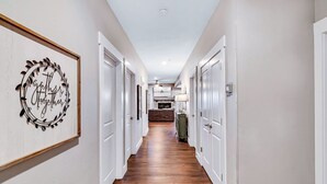 Un couloir avec des portes blanches, un plancher en bois et un panneau encadré accroché au mur.