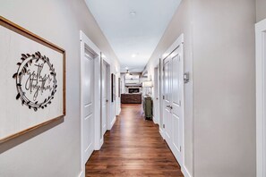 A hallway with white doors, a wooden floor, and a framed sign on the wall. - Top Lake View Retreat with 3 Decks, 2 Game Rooms, Theater, Free Tickets & Community Pool (Branson)