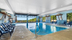 Une piscine intérieure à l’eau d’un bleu limpide, entourée de chaises longues et dotée d’un sol en béton.