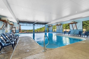 An indoor swimming pool with clear blue water, surrounded by lounge chairs and a concrete floor. - Top Lake View Retreat with 3 Decks, 2 Game Rooms, Theater, Free Tickets & Community Pool (Branson)