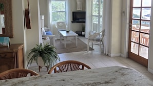 Un soggiorno spazioso con una grande finestra, una televisione e un'area pranzo con tavolo e sedie.