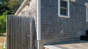 A house with a wooden fence, a window, and stone steps leading to the entrance. - Newly Renovated Cottage on Town Cove! (Eastham)