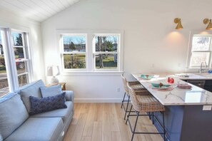 Eine moderne Küche mit Essbereich, einer Couch und Blick ins Freie.