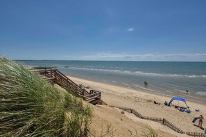 A beach with a wooden walkway, a sandy beach, and the ocean.