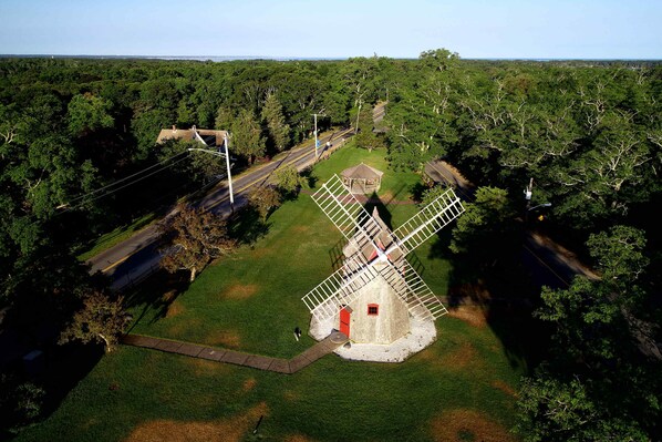 Eine Windmühle, umgeben von einer grünen Wiese, mit einer Straße in der Nähe.