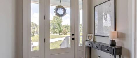 A front door with a wreath, a framed map, and a lamp on a console table.
