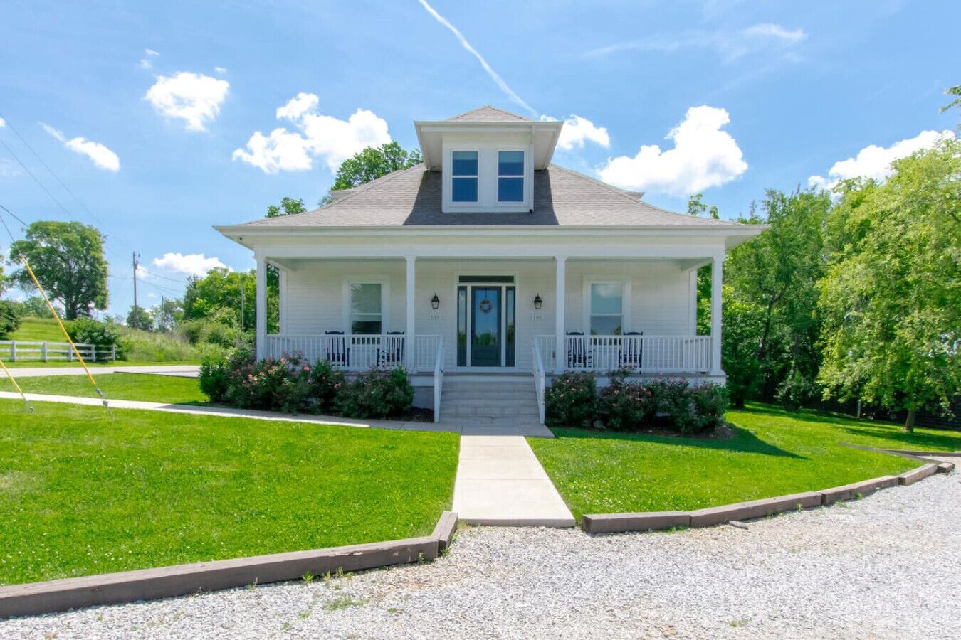A two-story house with a front porch, a front door, and a small front yard.