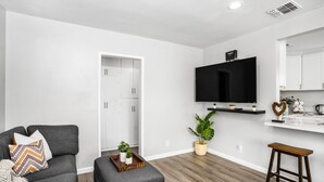 Een moderne woonkamer met een grijze bank, een houten salontafel en een aan de muur bevestigde televisie.
