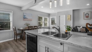 Een moderne keuken met een marmeren aanrecht, een roestvrijstalen spoelbak en hanglampen.