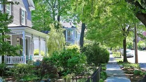 A residential street lined with houses, a sidewalk, and a small stream. - Cozy Historic Oakwood Duplex (Raleigh)