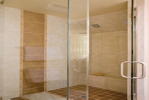 Un área de ducha con paredes y piso de azulejos, una barra para toallas y un cabezal de ducha.