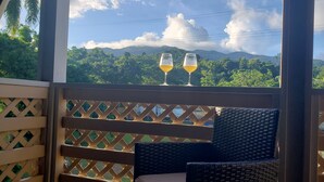 A balcony with wicker furniture and two glasses of wine, overlooking a lush green landscape with mountains. - Grand Chalet,  Private Pool, AC, River Access, Pool Table BBQ WIFI Parking (Rio Grande)