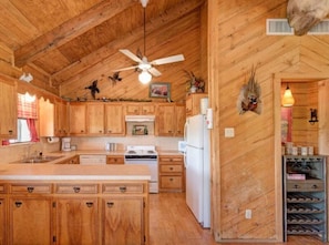 Enjoy cooking in this well-equipped kitchen with a central island, stove, refrigerator, and ceiling fan.
