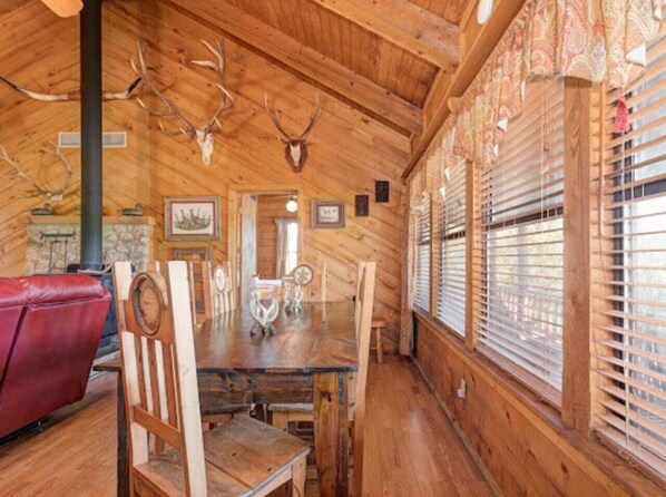 Cozy cabin-style room with a dining table, comfortable sofa, and wooden paneling.