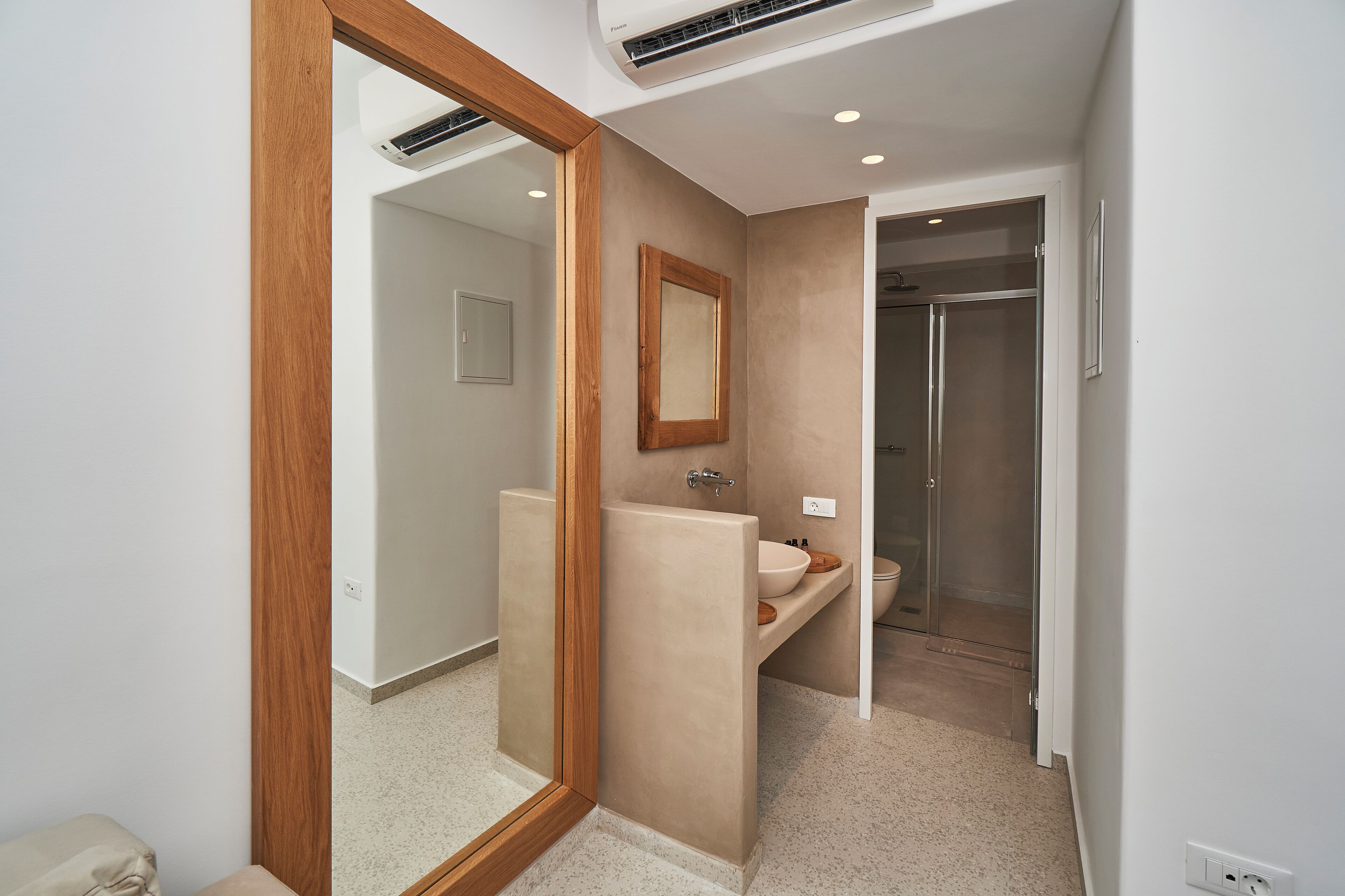 Un baño moderno con un espejo grande, un lavabo y una ducha.