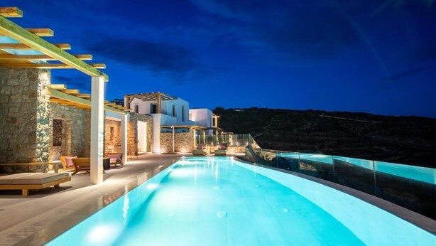 A modern pool area with a clear view of the surrounding architecture and a stone wall. - Due Mari Mykonos (Mykonos)