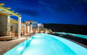 A modern pool area with a clear view of the surrounding architecture and a stone wall. - Due Mari Mykonos (Mykonos)