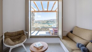 A balcony with a stone wall, a white chair, a sofa, and a small table with a book. - Due Mari Mykonos (Mykonos)