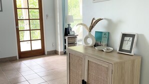A hallway with a wooden cabinet, a door with a view, and two framed pictures on the wall.