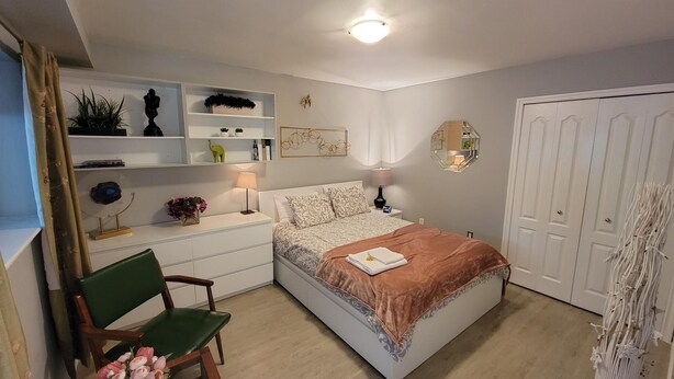 Een slaapkamer met een bed, nachtkastjes, een stoel, een bureau en een kledingkast.