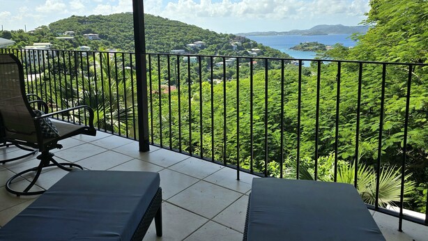 Ein Balkon mit Blick auf eine Küstenlandschaft, inklusive eines Gewässers und eines Hügels mit Gebäuden.