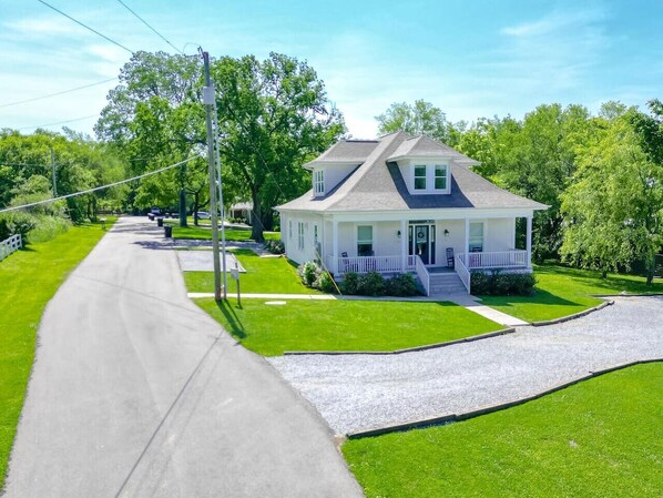 A two-story house with a front porch, a driveway, and a well-maintained lawn.