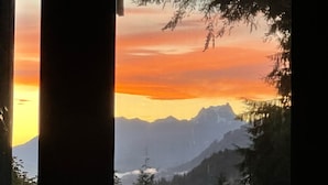 A view of a mountain range at sunset with a forested foreground.
