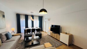 Un salon moderne comprenant un canapé, une table basse, un téléviseur et un coin repas.