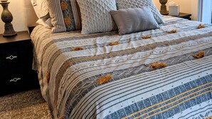 A neatly made bed with patterned bedding, two bedside tables with lamps, and a window with daylight. - Family Friendly FULL HOUSE (Warren)