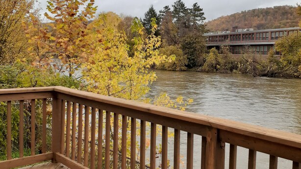 A wooden deck with a view of a river and a building across the water. - Family Friendly FULL HOUSE (Warren)