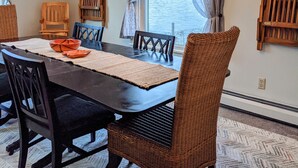 A dining area with a large table, chairs, and a view of a body of water through a window. - Family Friendly FULL HOUSE (Warren)