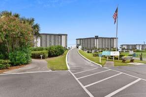 A hotel entrance with a curved driveway, a parking lot, and a large building with multiple floors.