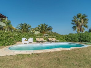 A swimming pool with lounge chairs and palm trees.