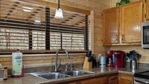 Una cocina con armarios de madera, un lavamanos doble y una cafetera.