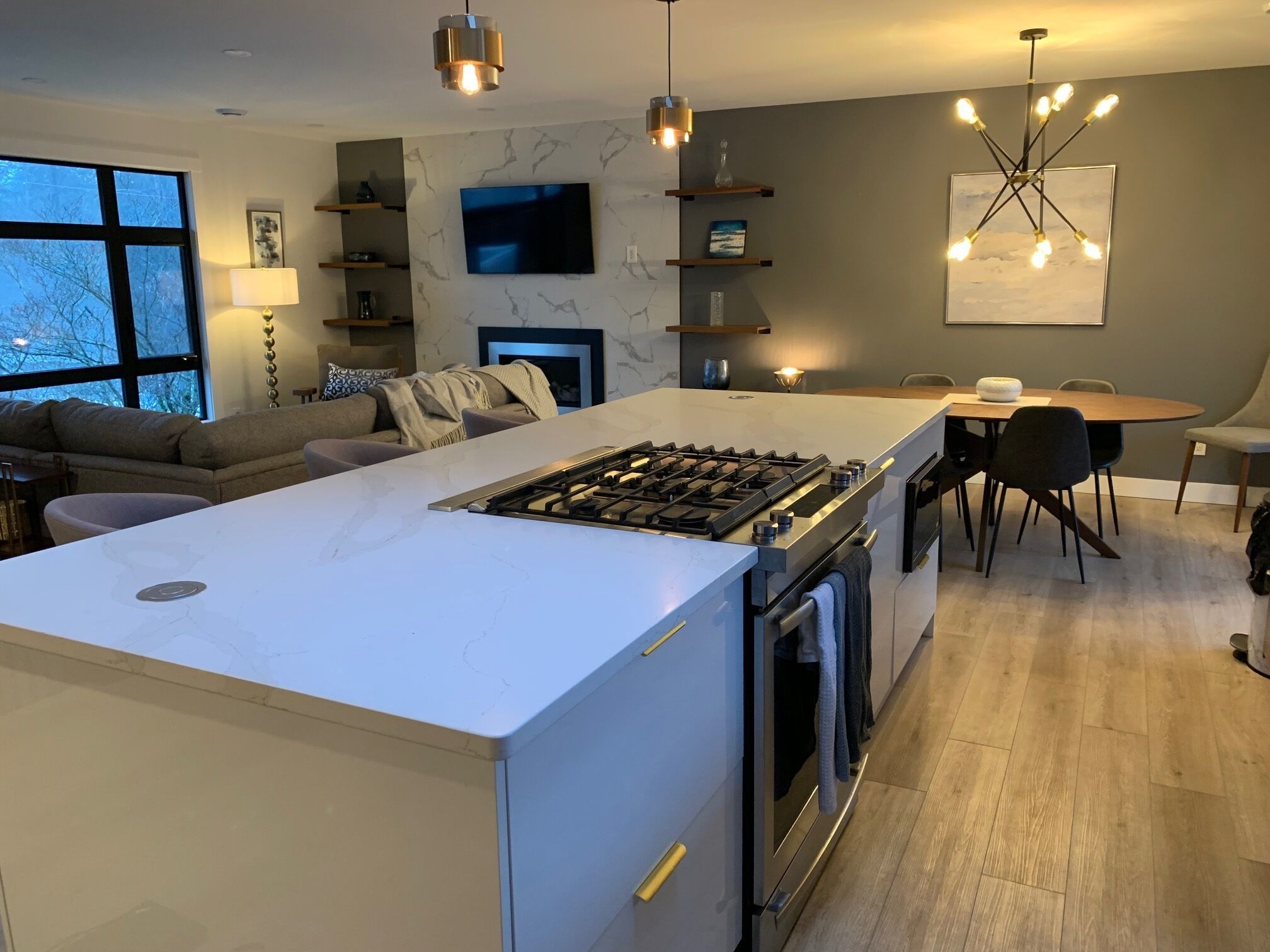 A modern kitchen with a central island, built-in oven, and a dining area with a table and chairs.