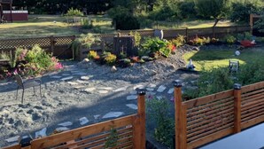 A garden with a wooden deck, stone pathway, and various plants.