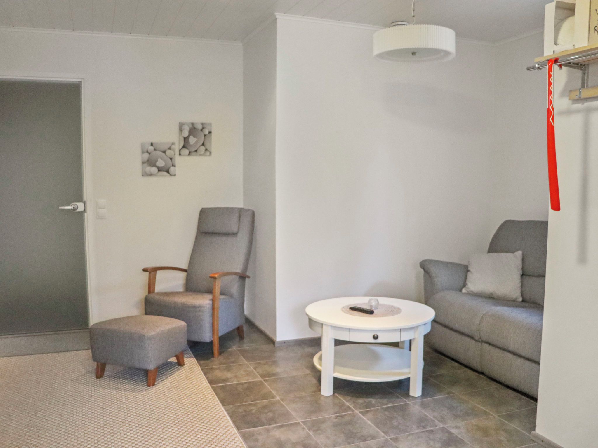 A living room with a grey sofa, a grey armchair, a small white table, and a grey ottoman.