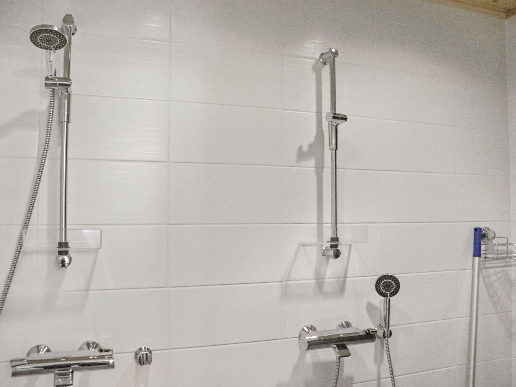 Une salle de bain équipée d’un système de douche comprenant un pommeau de douche à main, un pommeau de douche fixé au mur et un accessoire de douche à main.