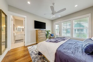 A bedroom with a bed, a ceiling fan, a TV, and a window with blinds. - Townhouse + loft with private balcony, heated pool, gym, beach access & W/D (Port Aransas)